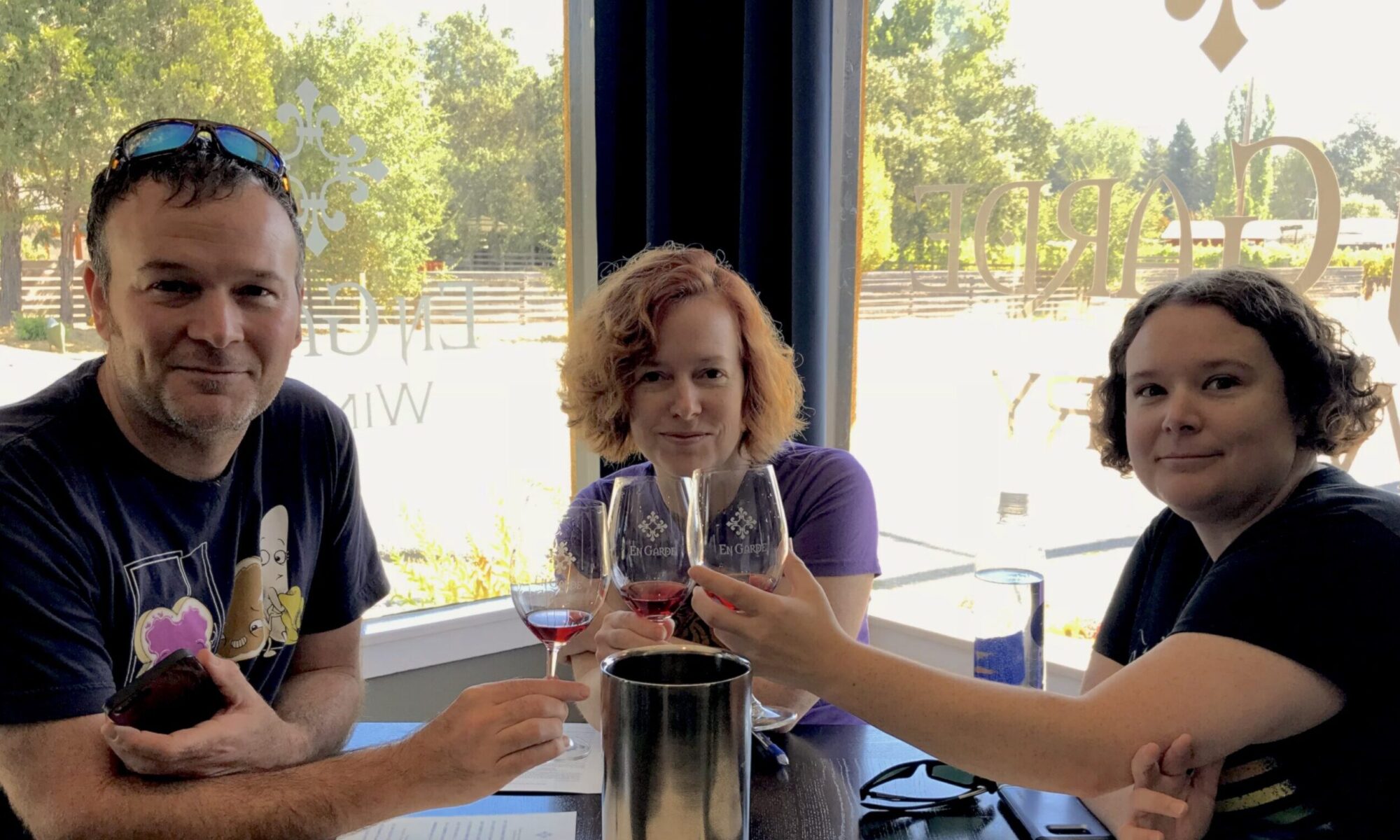 Edie White flanked by two people at a winery tasting room, each raising a glass.